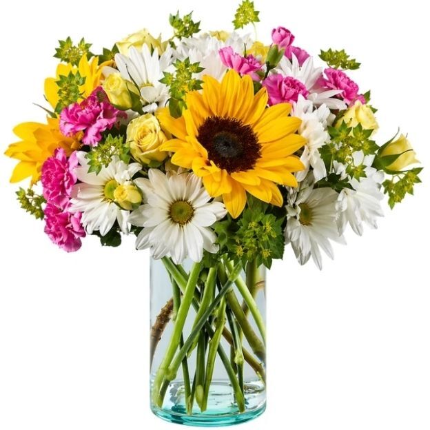 Bright bouquet with sunflower, white daisies, pink carnations, and pale yellow roses in a glass vase