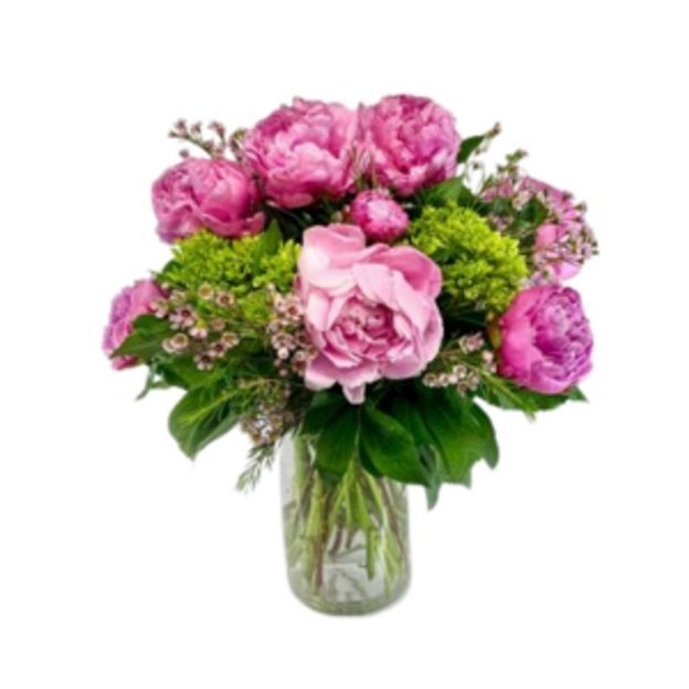 Bright pink and green floral arrangement with peonies and greenery displayed in a tall clear vase.