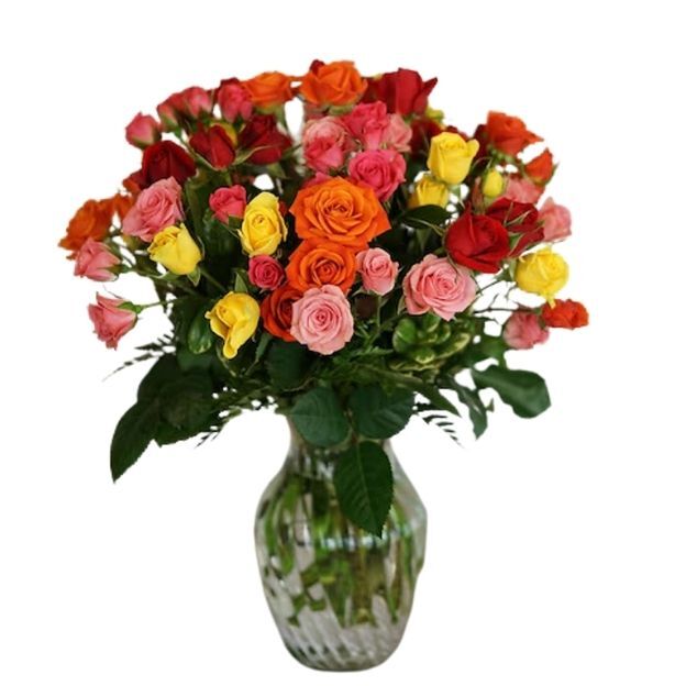 Colorful rose arrangement featuring vibrant red, orange, yellow, and pink roses in a clear ribbed glass vase.